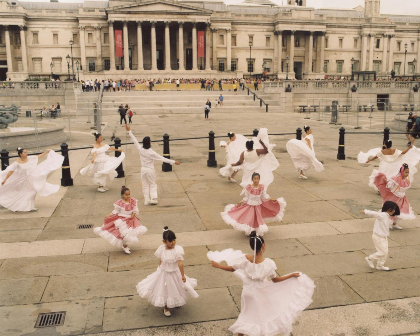 Image by Silvana Trevale of a group of children in dresses dancing in unison on Trafalgar Square