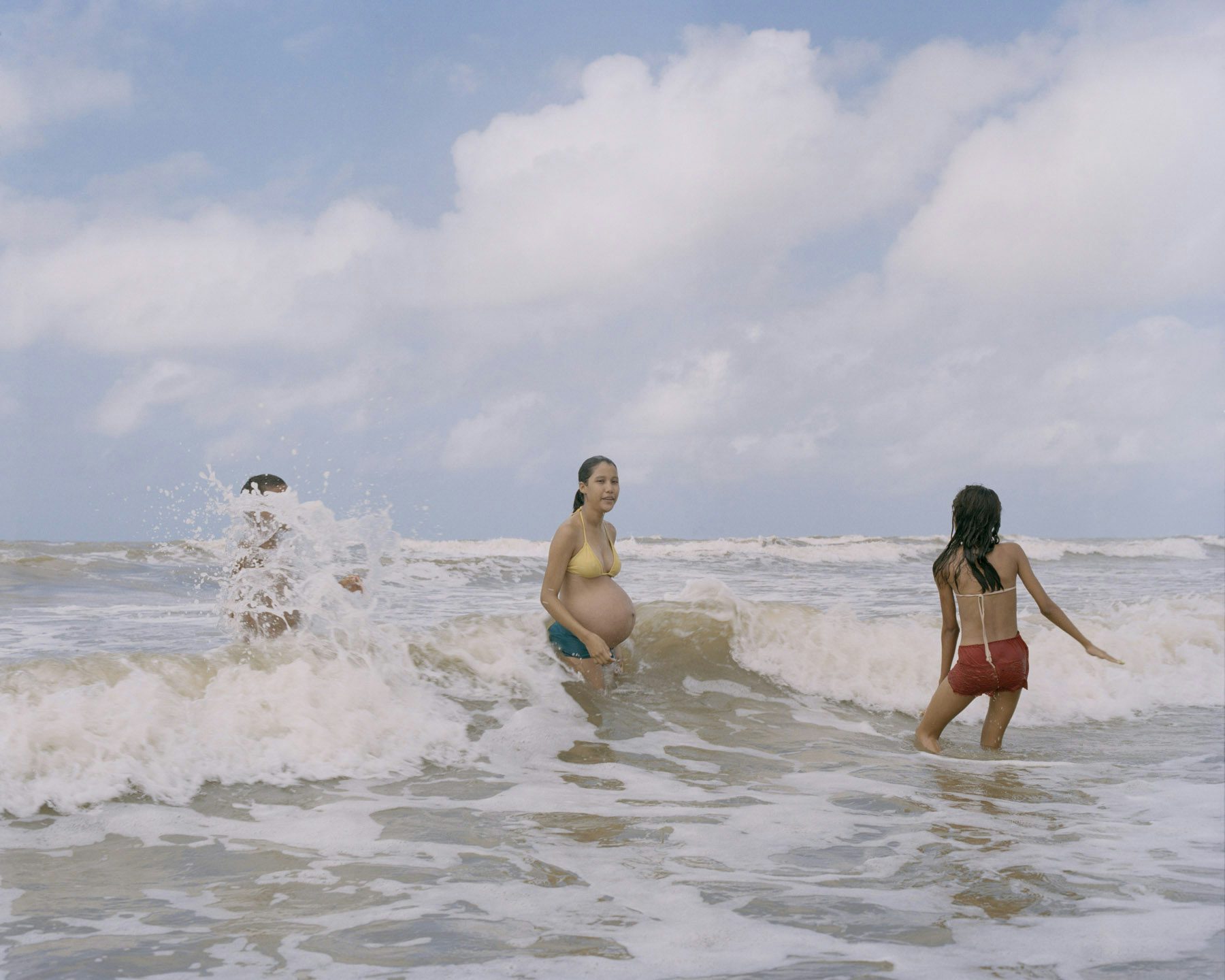 Image by Silvana Trevale of three people playing in the sea, including one pregnant person