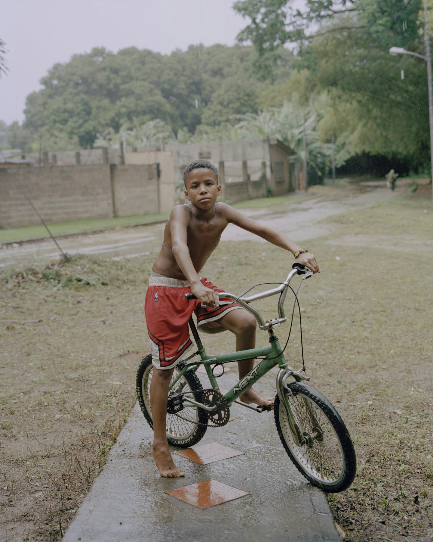 Image by Silvana Trevale of a young boy on a bike pausing on a wet pathway