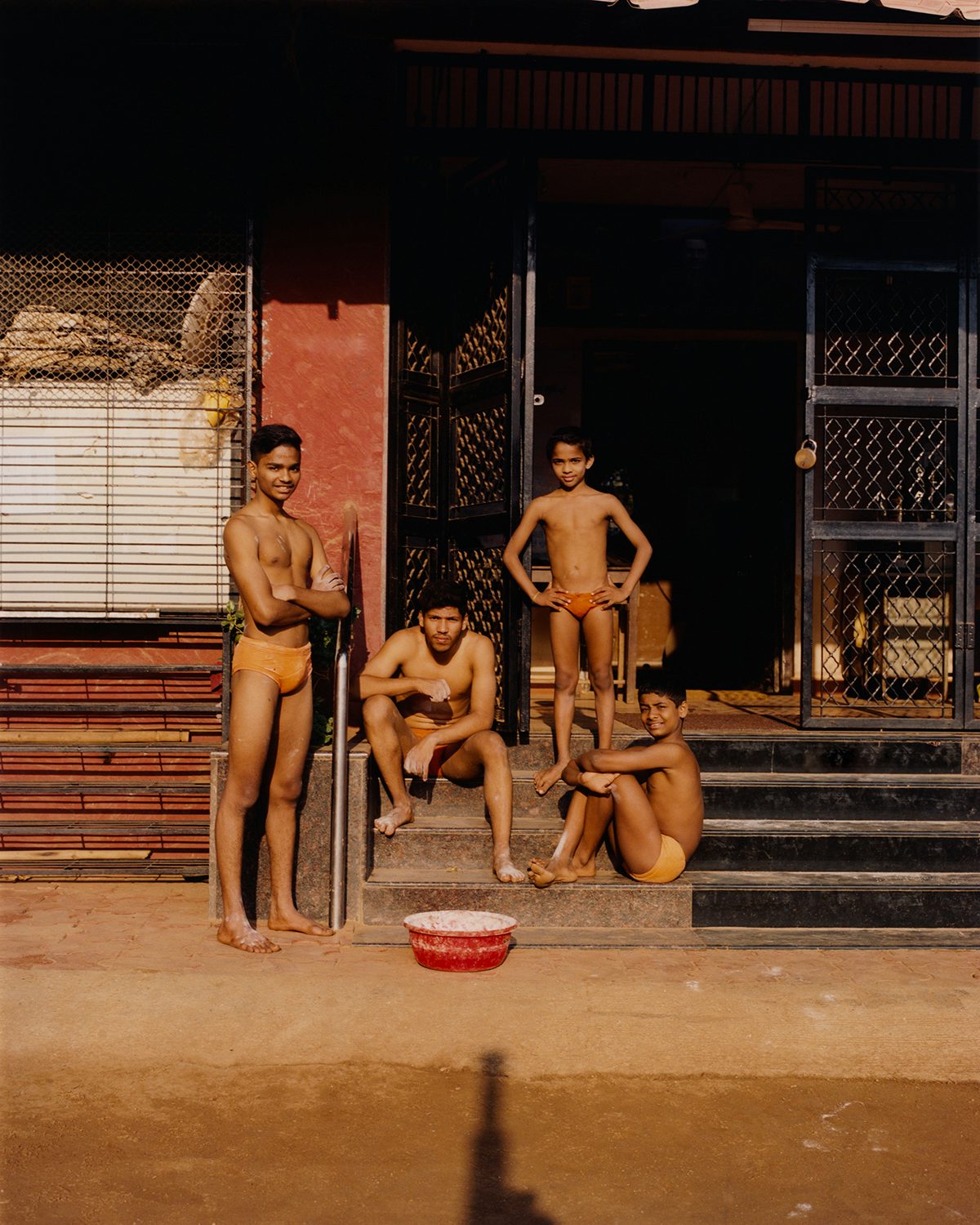 Photograph of four young people sat on steps in Vivek Vadoliya's book Mallakhamb