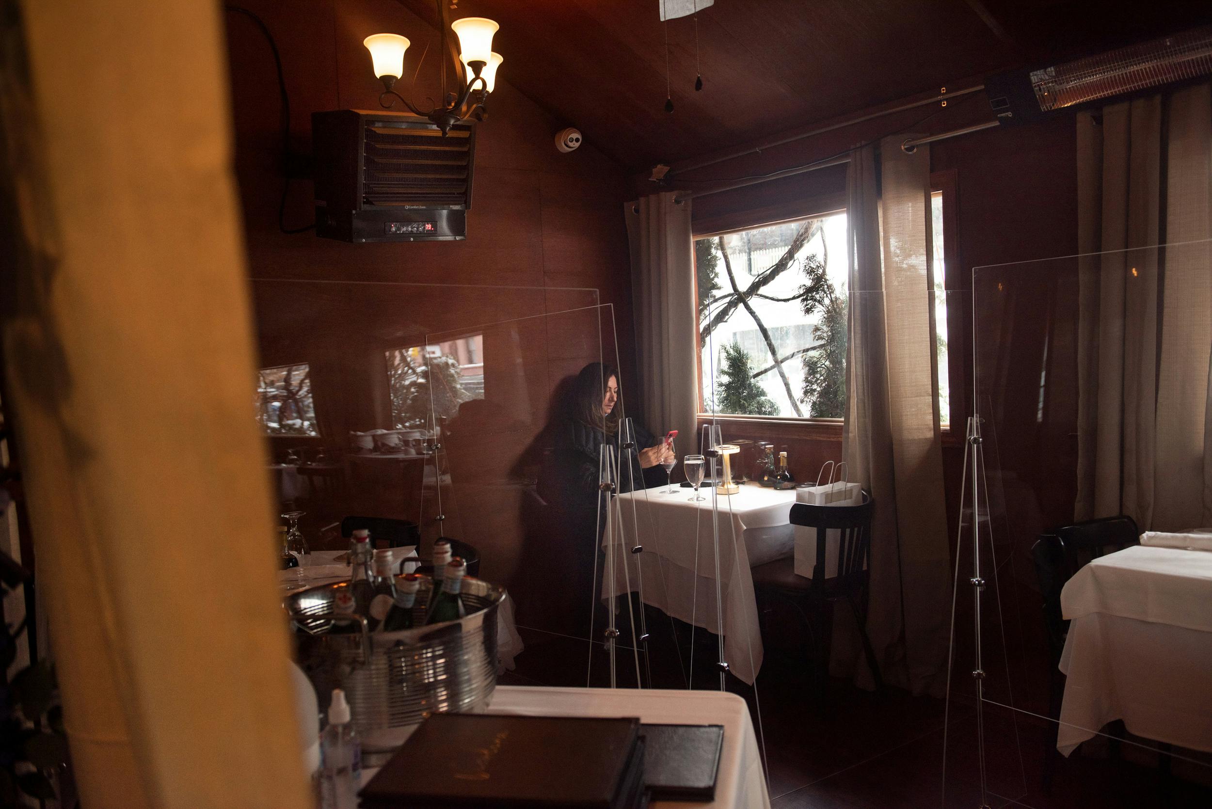 'The Cozy Corner Table' from the artist's 'DINING ALONE In the Company of Solitude' book project and series. The work highlights the experience of being alone in public. The peopled restaurant interiors are a metaphor for visually expressing what being alone in public might feel like.