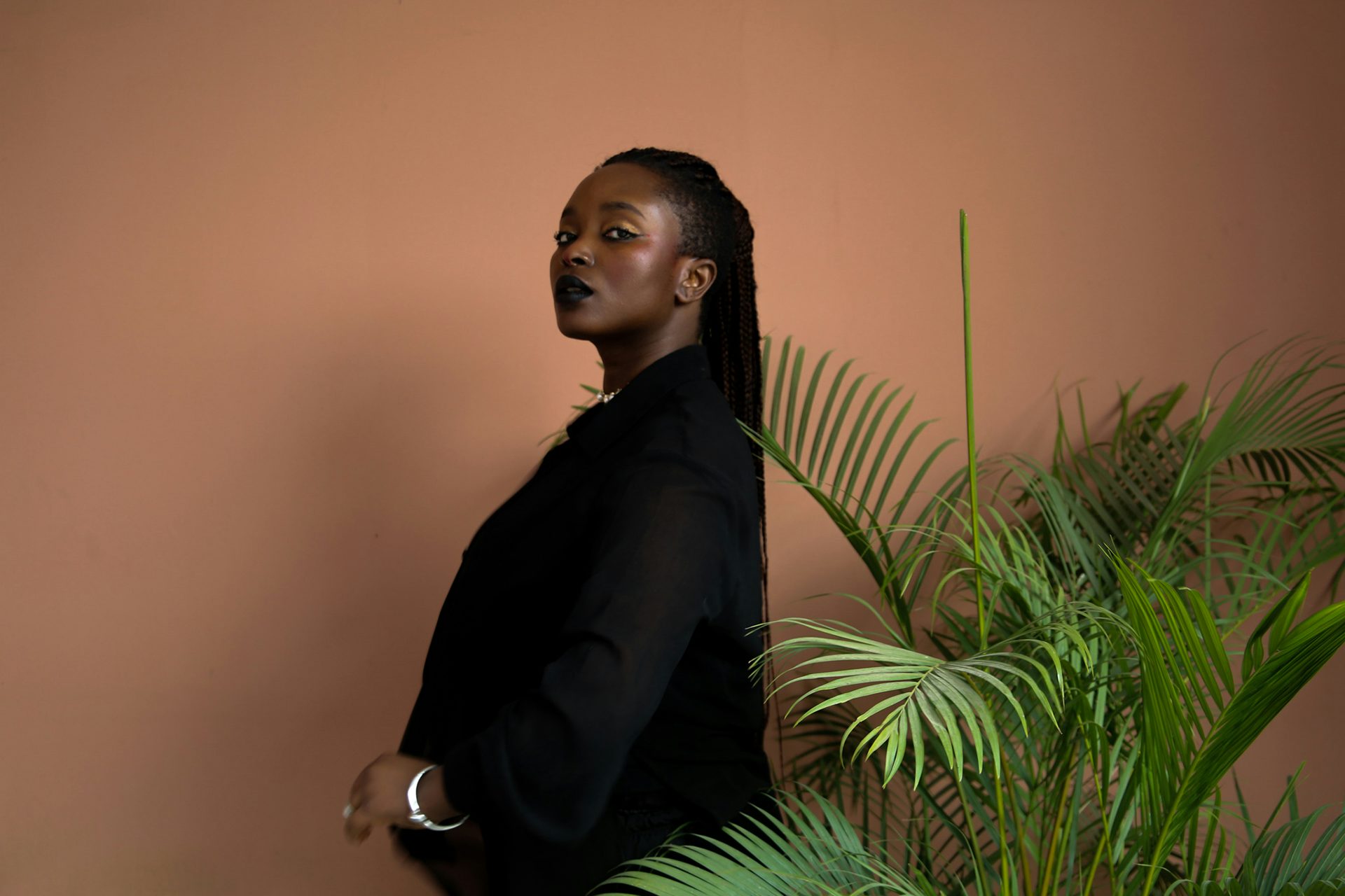 Photograph of Artist and writer Eloghosa Osunde stood next to a plant
