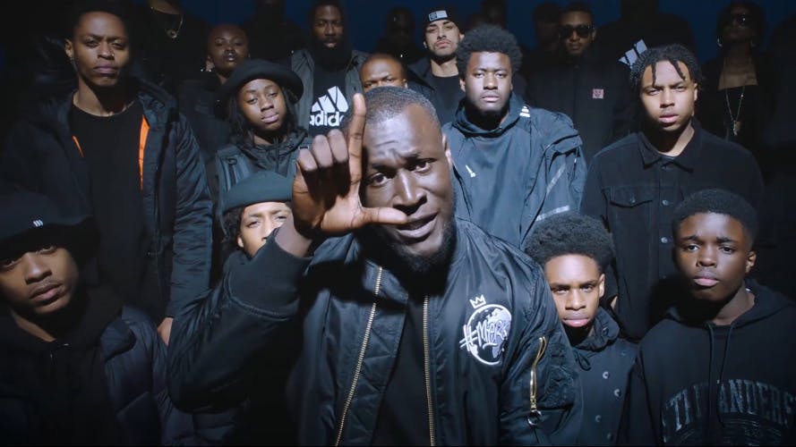 Still of Stormzy surrounded by young people in the music video for Vossi Bop by Henry Scholfield