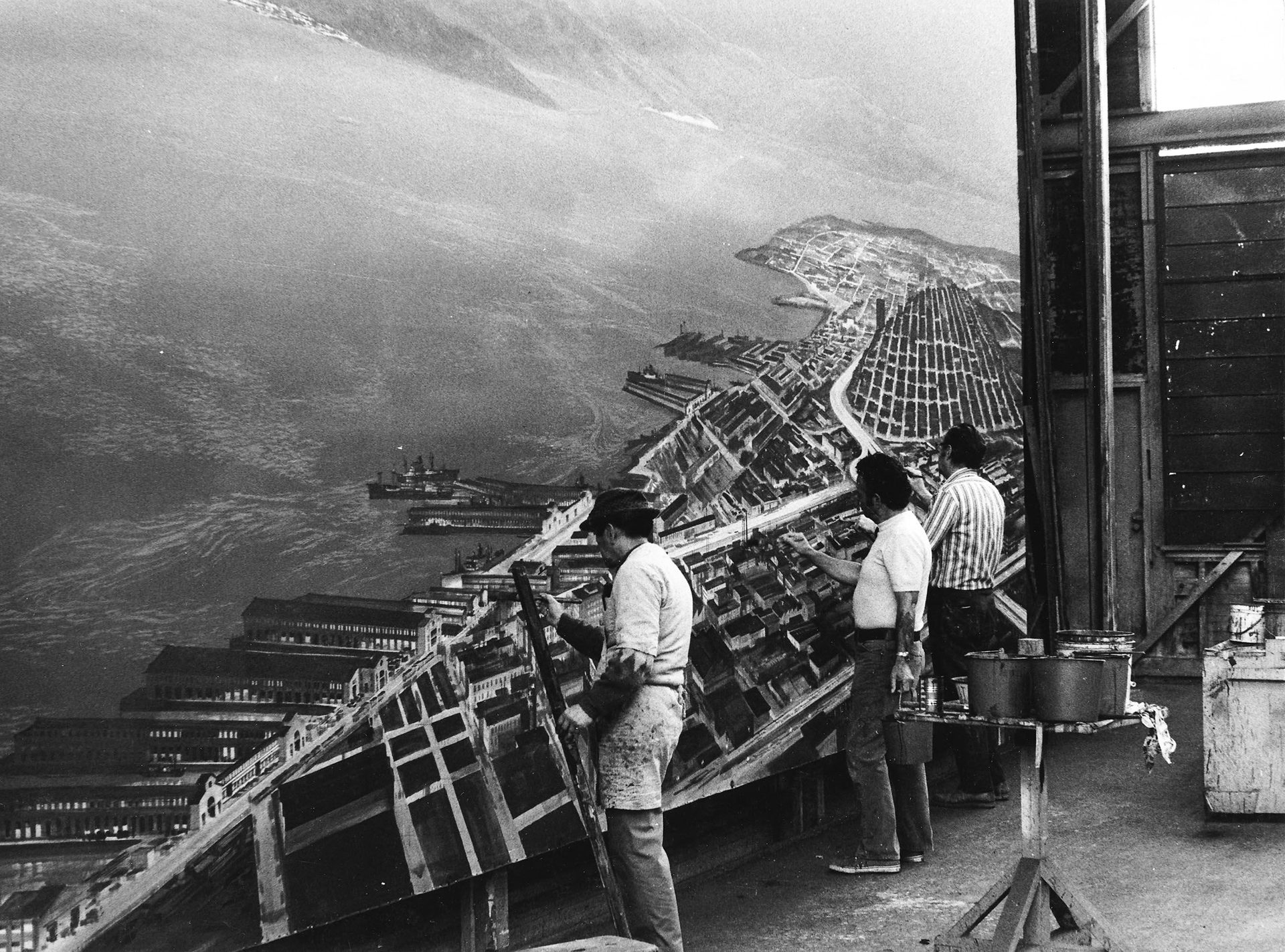 Black and white photograph of artists working on a coastal backdrop