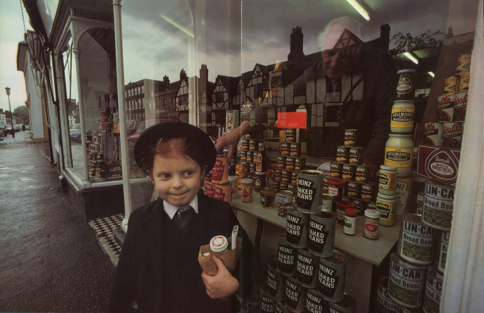 Photograph of a young person walking past a shop window filled with Heinz tins by Magnum photographer Burt Glinn