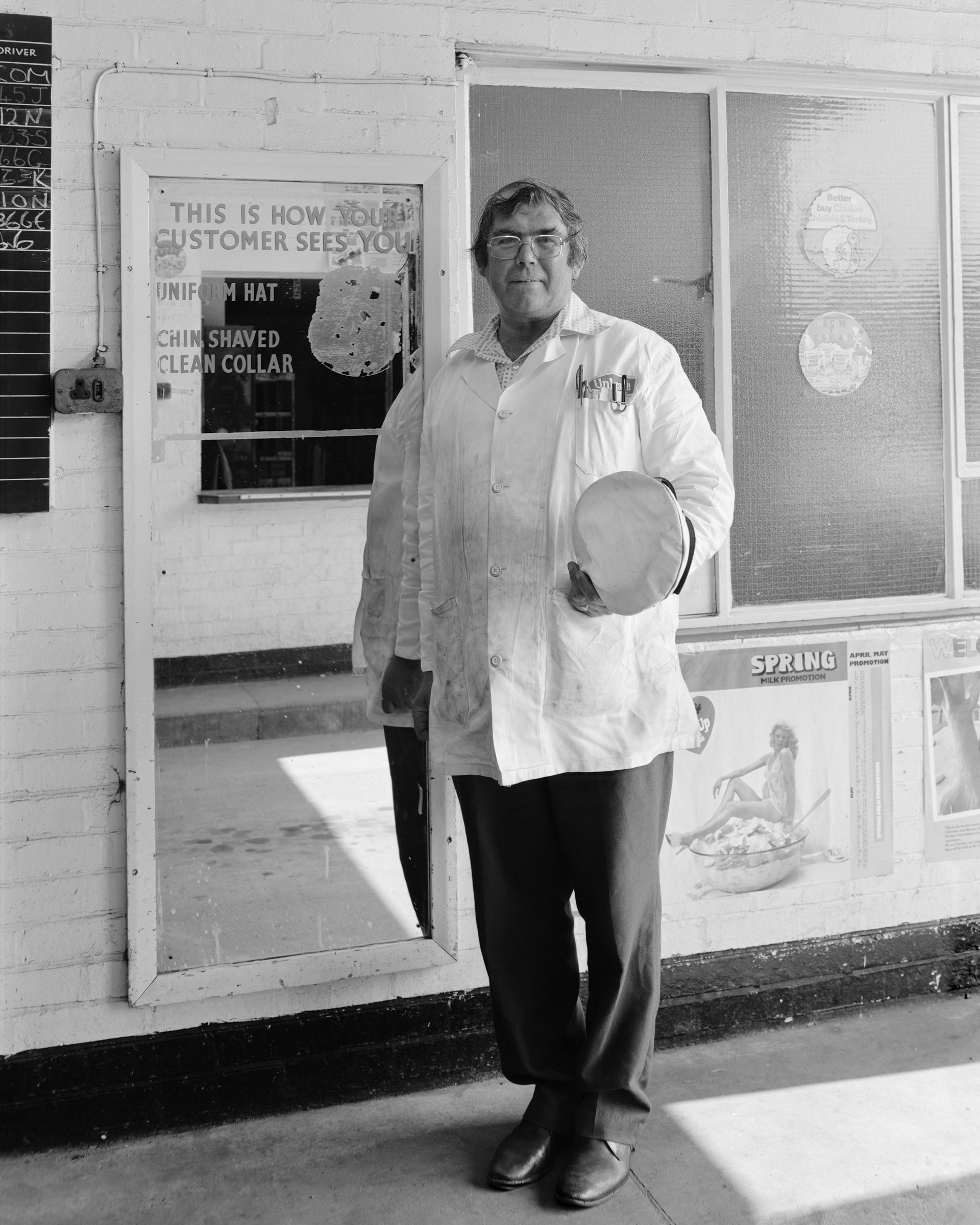 Black and white photograph of a milkman carrying a hat, which features in Life As It Is by John Myers