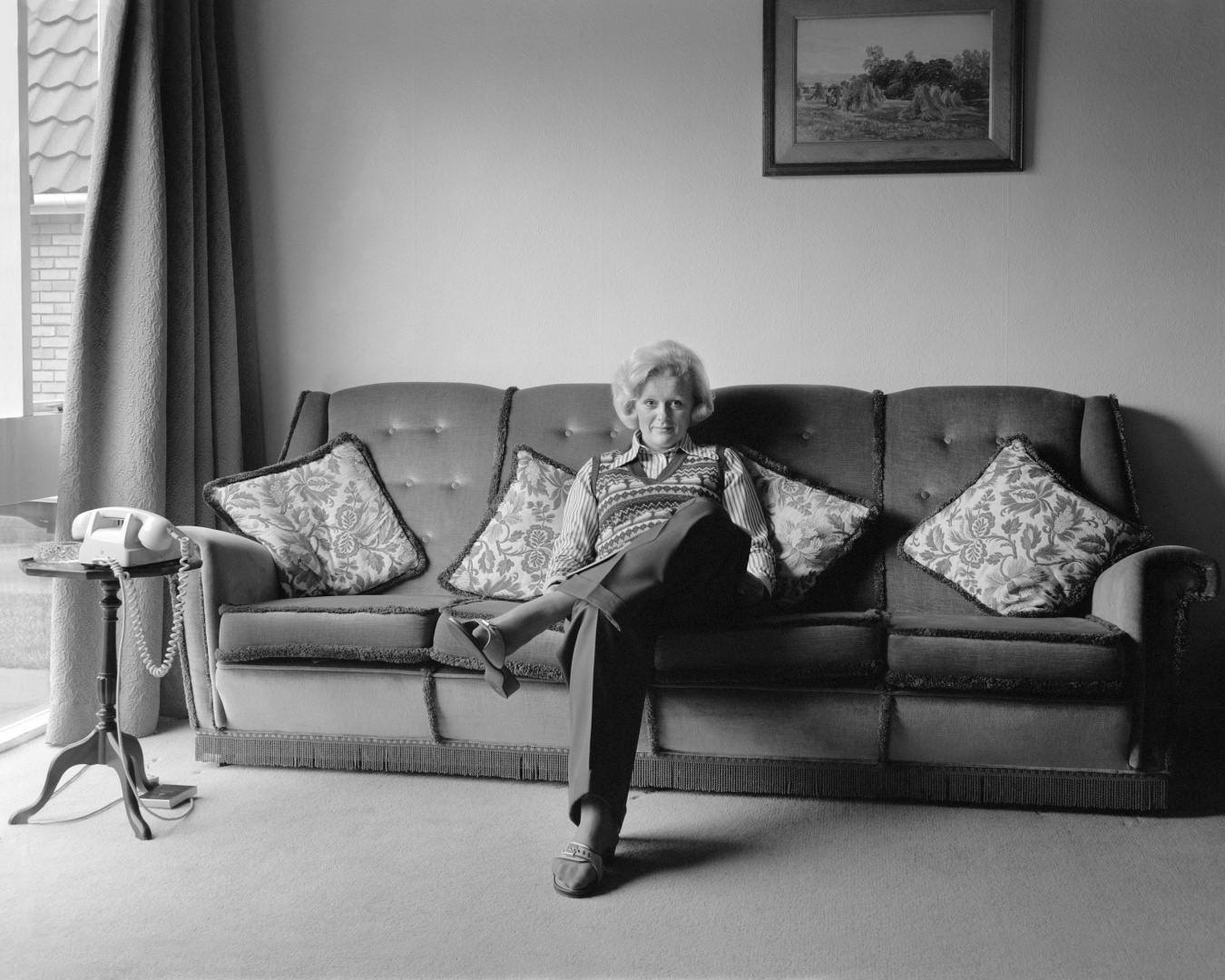 Black and white photograph of a woman sat on a sofa, which features in Life As It Is by John Myers