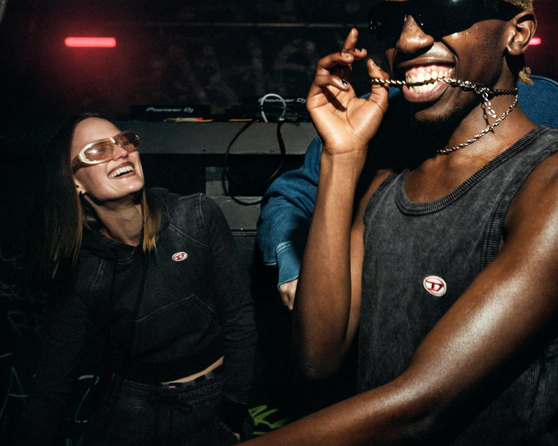 Photo of a young person chewing a neck chain in a club for Diesel's Track Denim campaign by Ewen Spencer