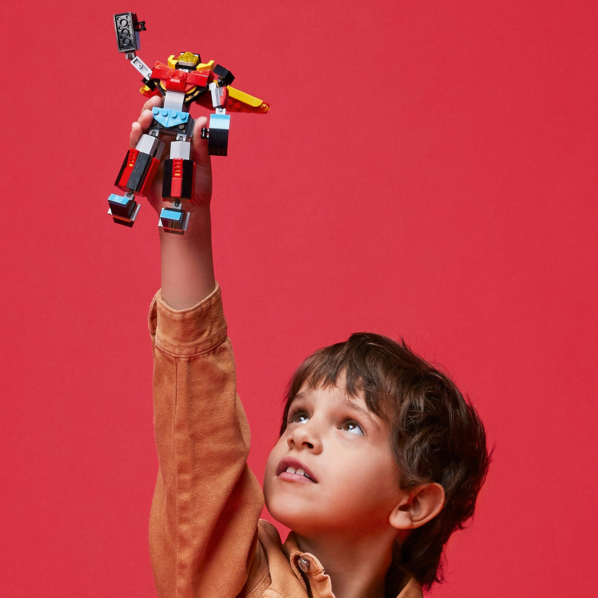Photograph of a child holding up a Lego figurine overhead