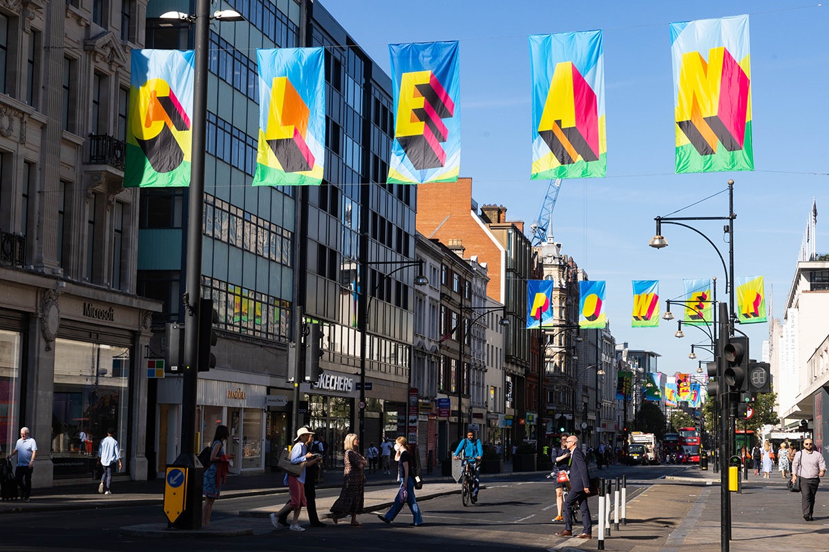 Photograph of Morag Myerscough's installation on Oxford Street, featuring colourful flags that read 'Clean' in the foreground