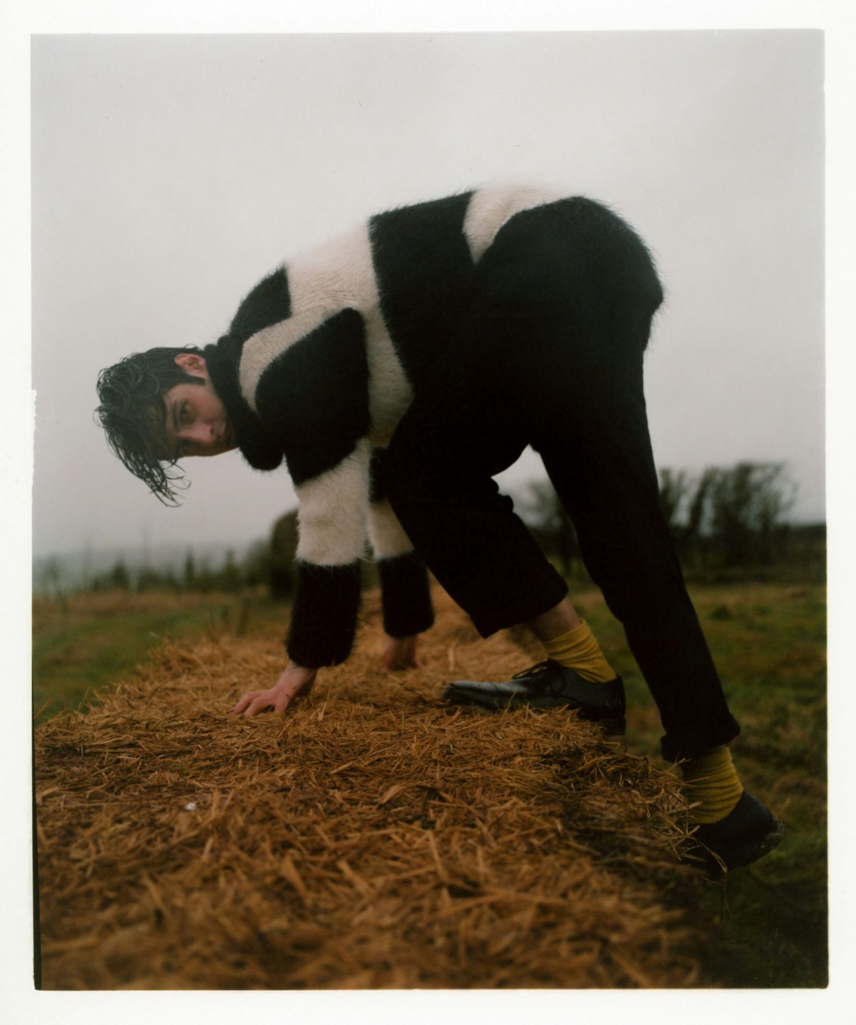 Photograph by Niall Hodson of a person wearing a black and white sweater climing in a field