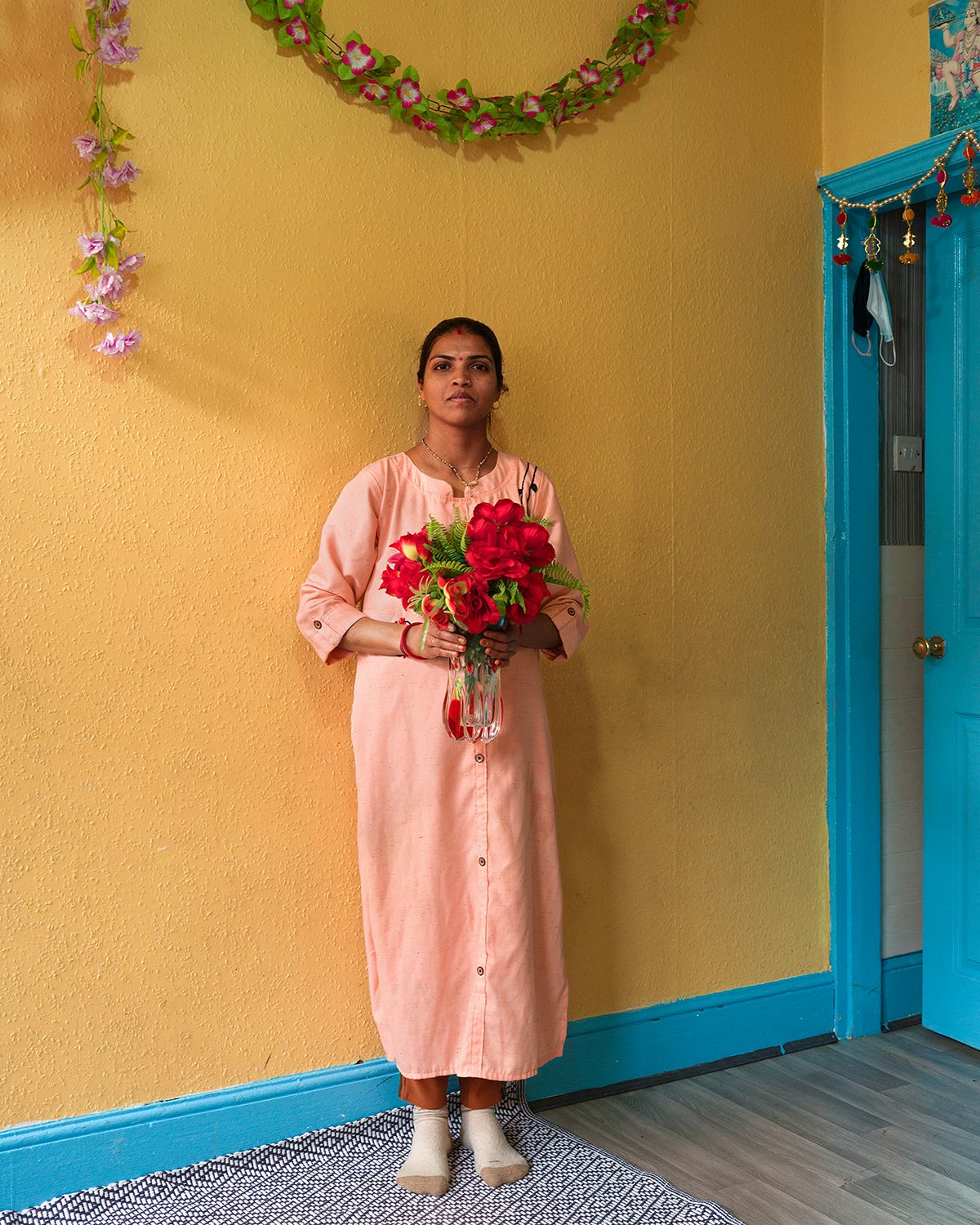 Image shows a person wearing a pink outfit holding a bouquet of flowers, taken from Kavi Pujara's book This Golden Mile