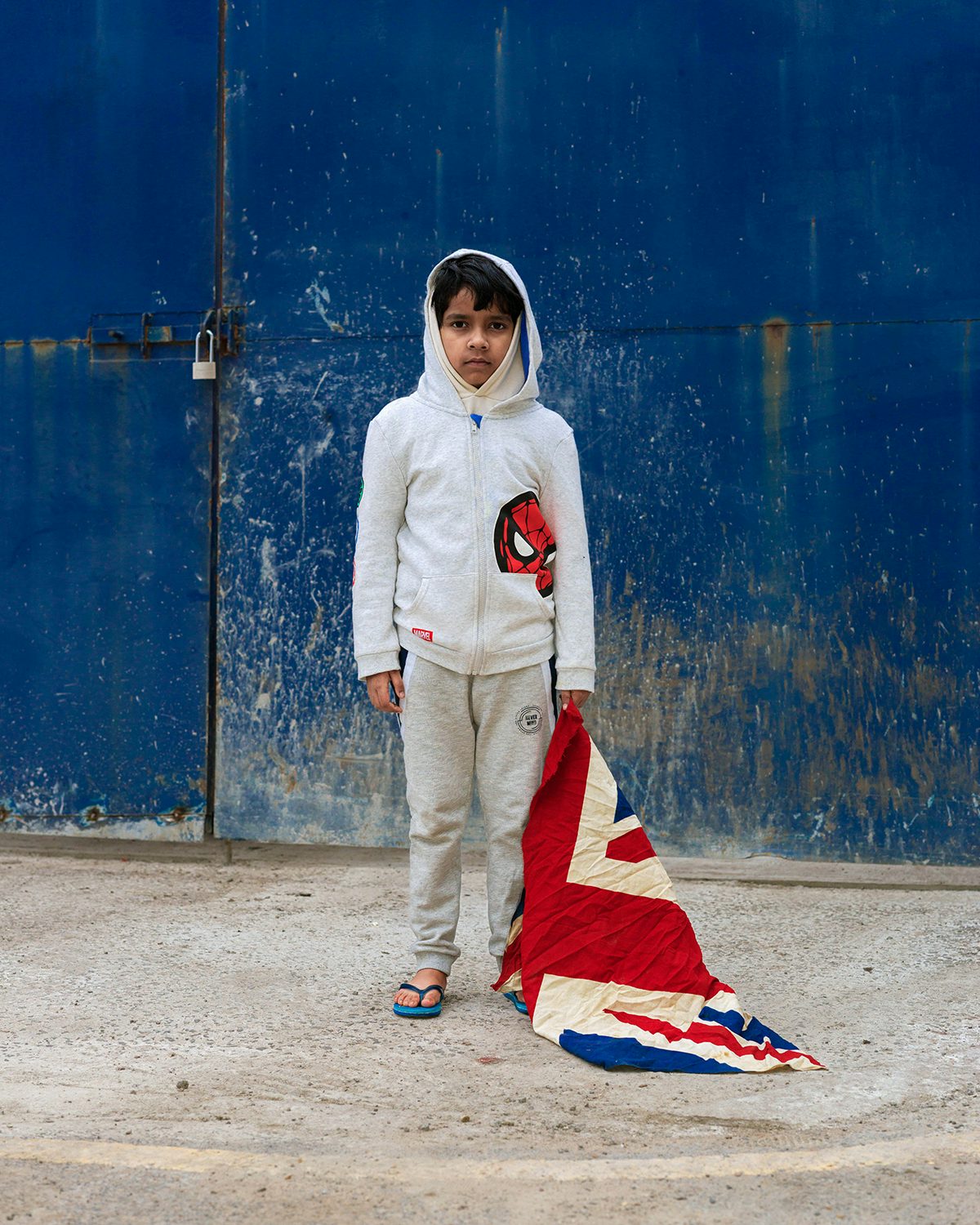 Image shows a young boy wearing a Spiderman hoodie holding a Union Jack flag, taken from Kavi Pujara's book This Golden Mile