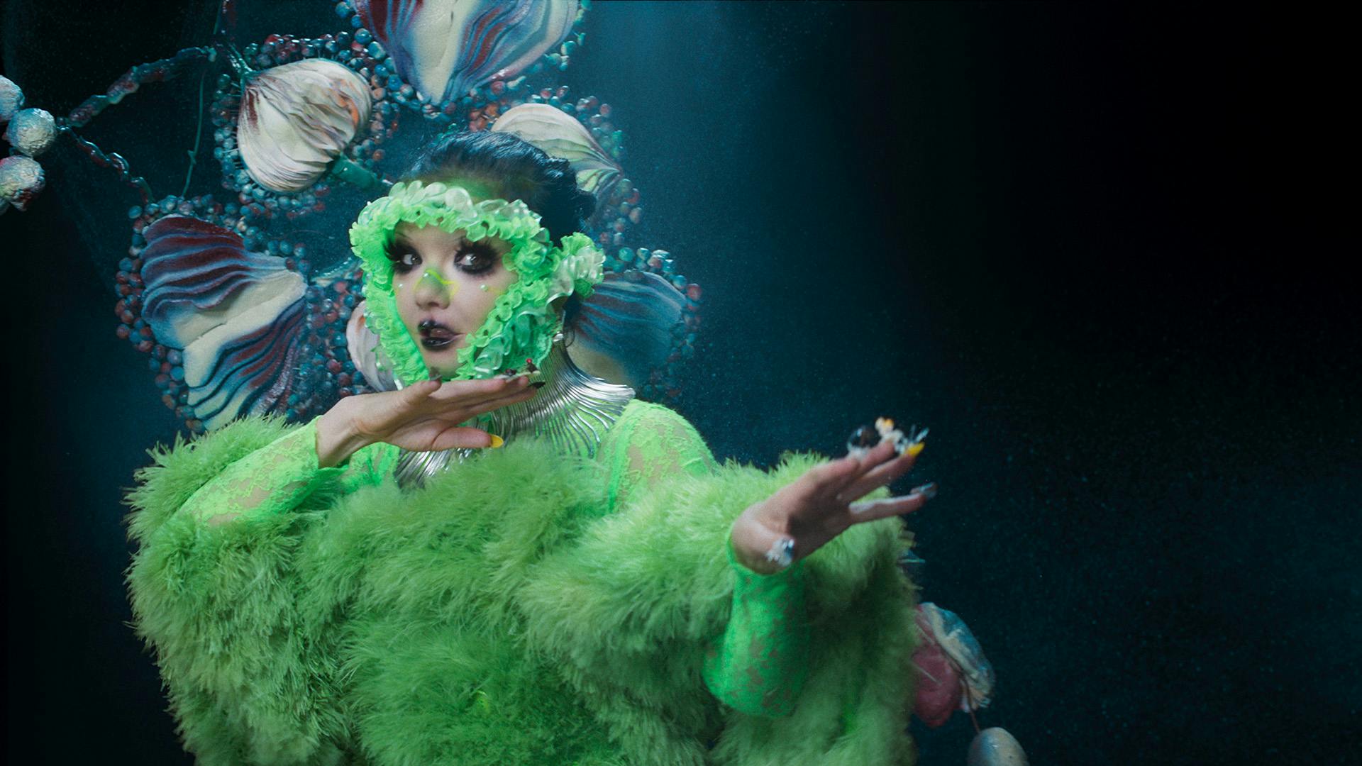 Still image of Bjork wearing a green dress and headwrap from the music video for Atopos by Bjork directed by Vidar Logi