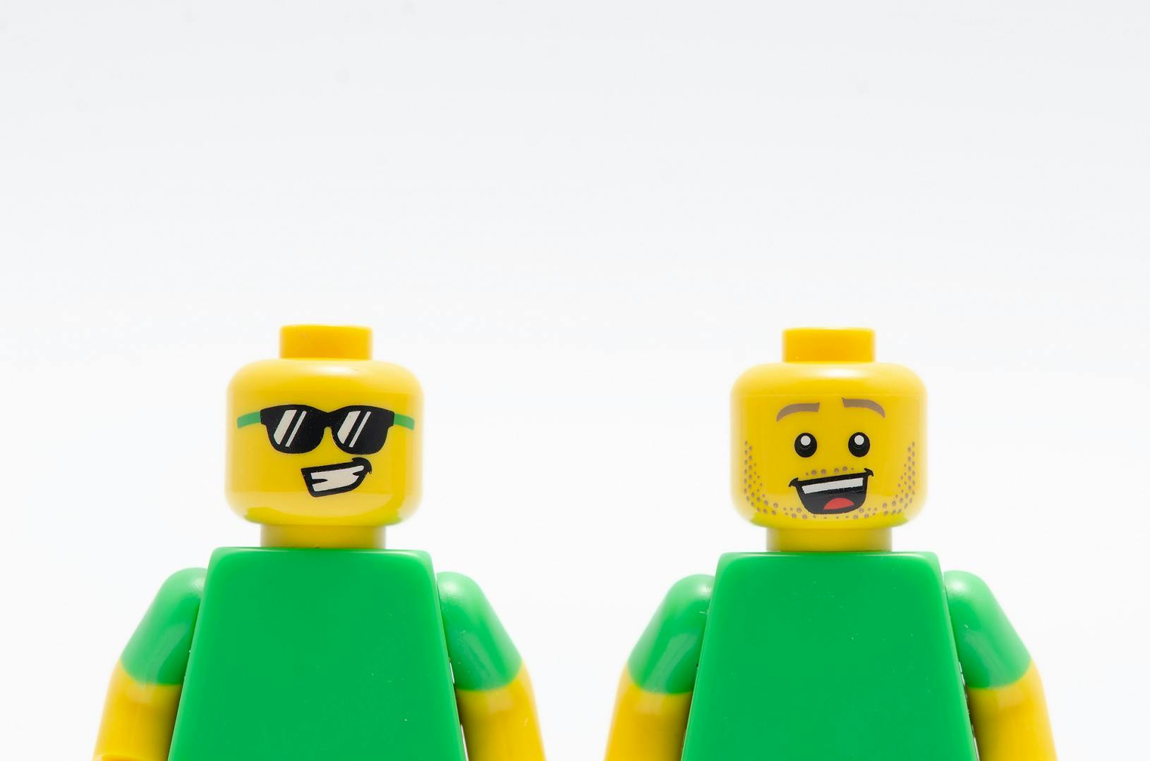 Image shows two smiling LEGO figures wearing green shirts