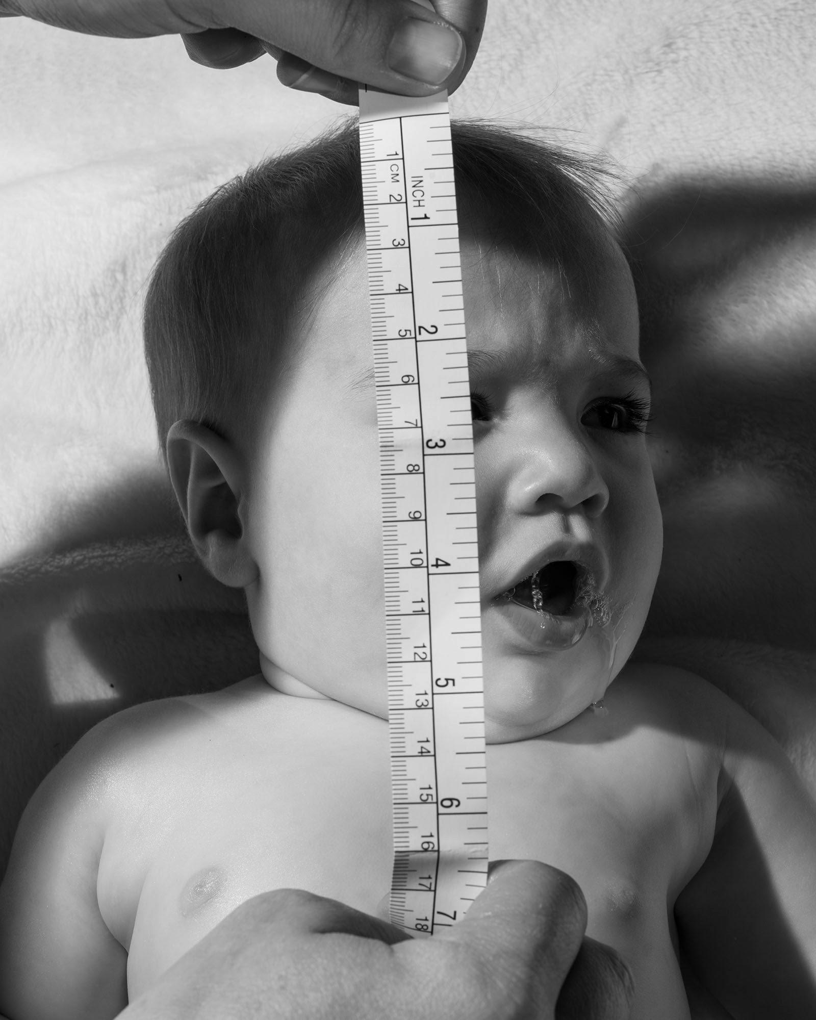 Black and white photograph of someone measuring a baby's head, in the Four Pillars book by Eli Durst