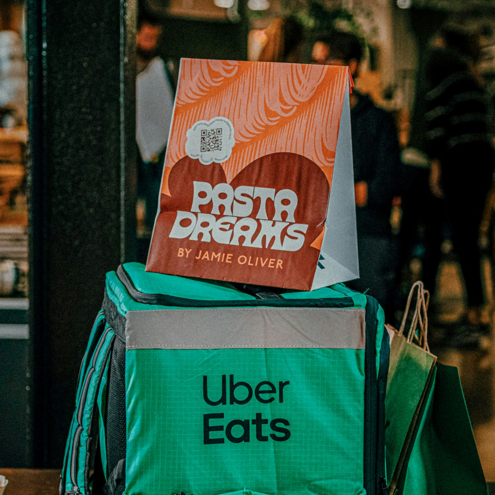 Image shows a paper bag that reads 'Pasta Dreams' on top of an Uber Eats delivery bag