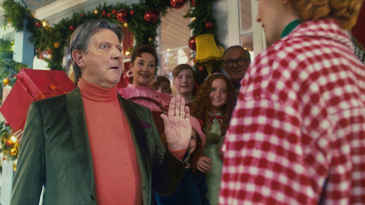 Image shows a man in a green jacket holding up his hand in the TK Maxx Christmas 2022 advert