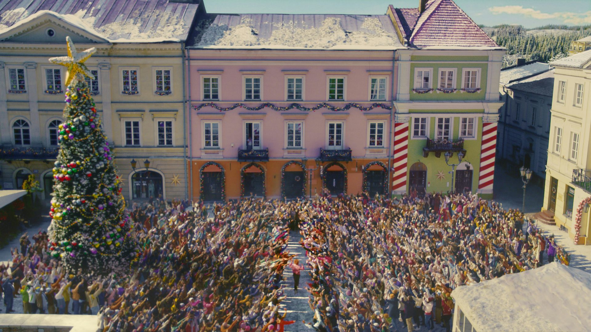 Image shows crowds of people stood in front of a colourful building, in the TK Maxx Christmas 2022 advert