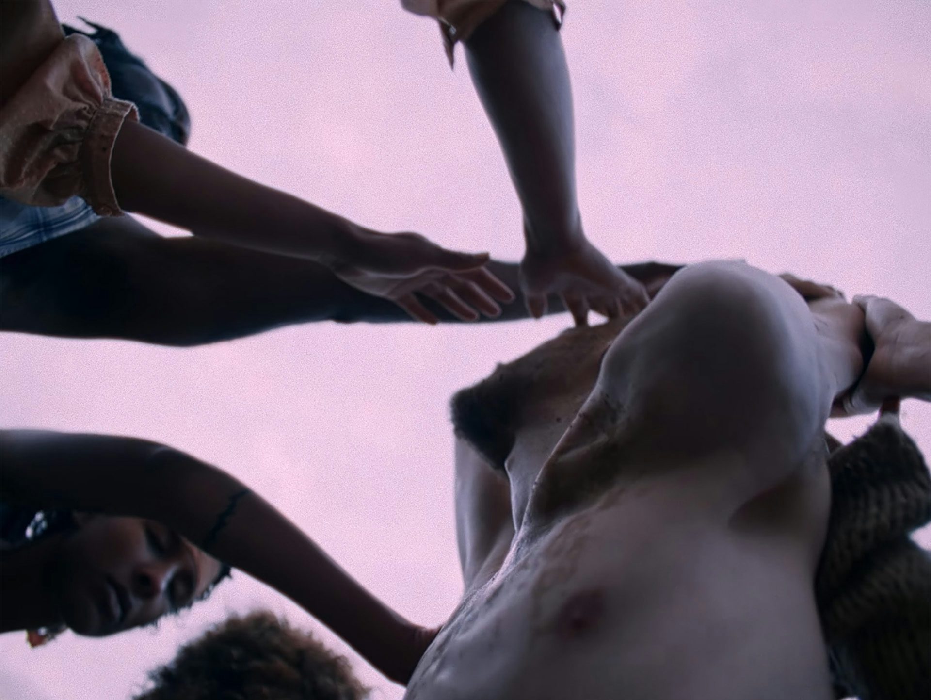 Still image shows a person being carressed by a group in the music video for I Saw by Young Fathers