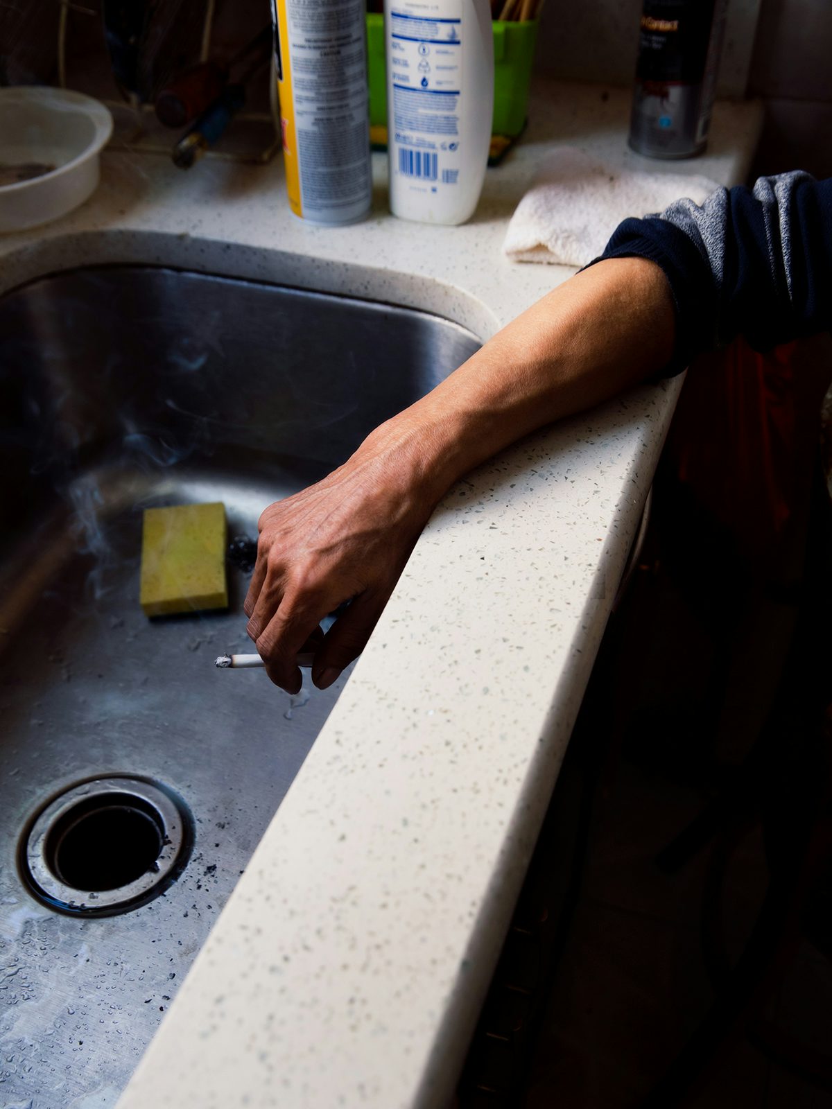 Image by Justin J Wee showing Mr Gao smoking a cigarette held over his kitchen sink