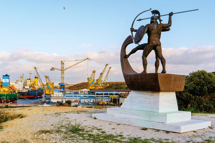 Image by Niko J. Kallianiotis showing statues of warriors overlooking an industrial part of Athens