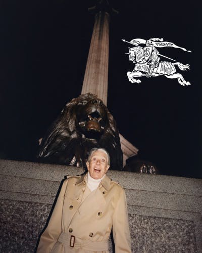 Image shows Vanessa Redgrave stood by the lion statue at the bottom of Nelson's Column. To the top right hand side of the image is the new Burberry logo in white, showing a knight riding a horse and carrying a flag that reads 'Prorsum'