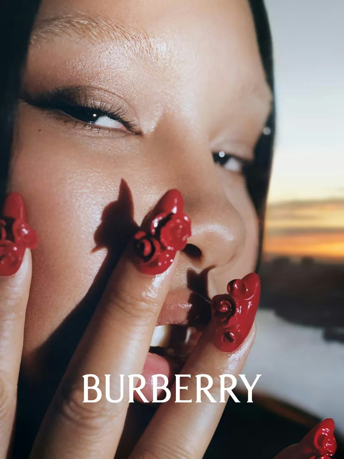 Image shows a close-up portrait of Shygirl wearing nails embellished with roses, next to the new Burberry wordmark