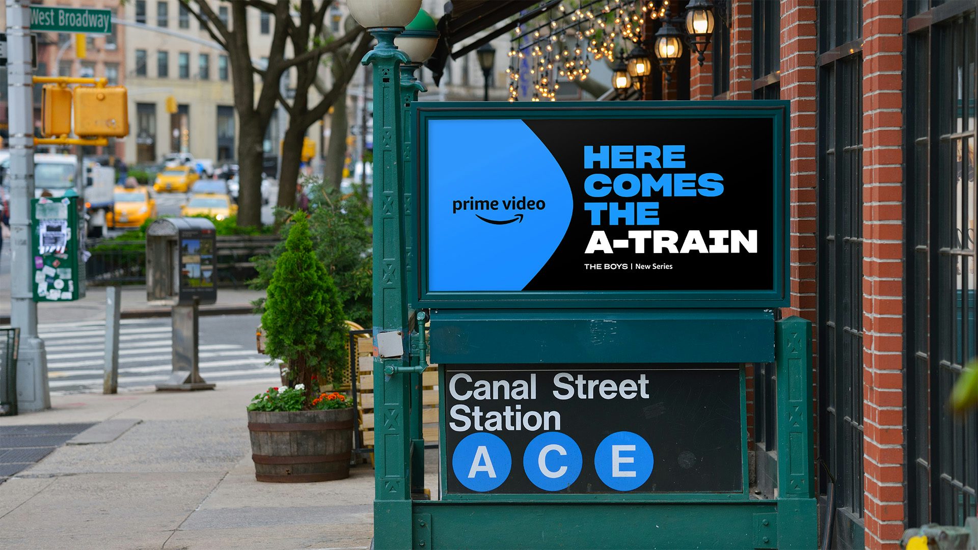 Image shows an outdoor advert featuring the new Prime Video branding. The ad reads 'Here Comes The A-Train' in blue and white text on a black background