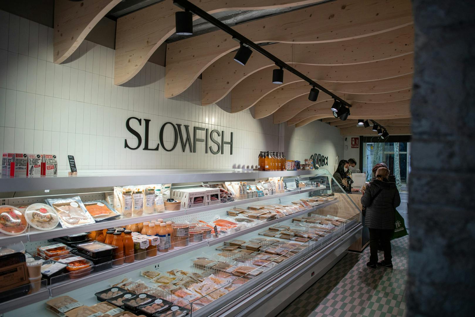 Photograph of a shop counter with Slowfish branding by Vasava featured on the wall behind
