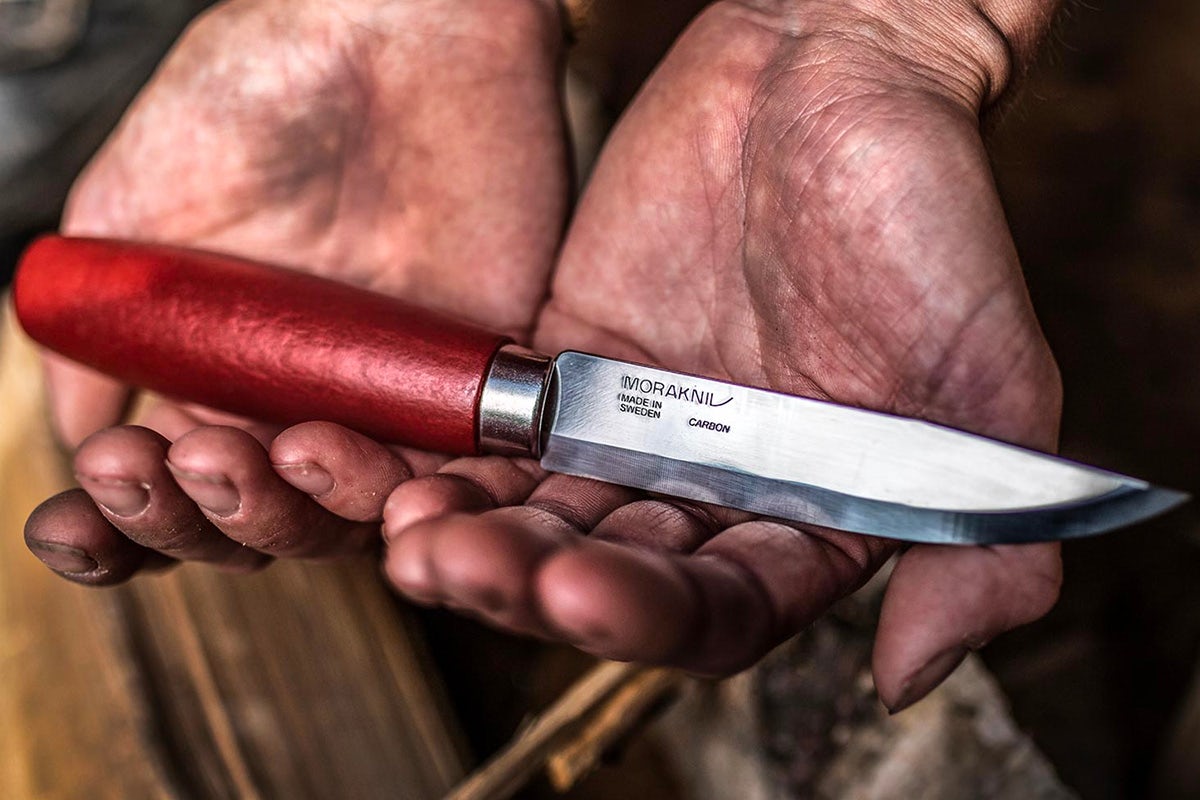 Photograph of a person holding a Morakniv knife in their hands, which features the brand's new wordmark including an angular 'V' at the end in the shape of a blade