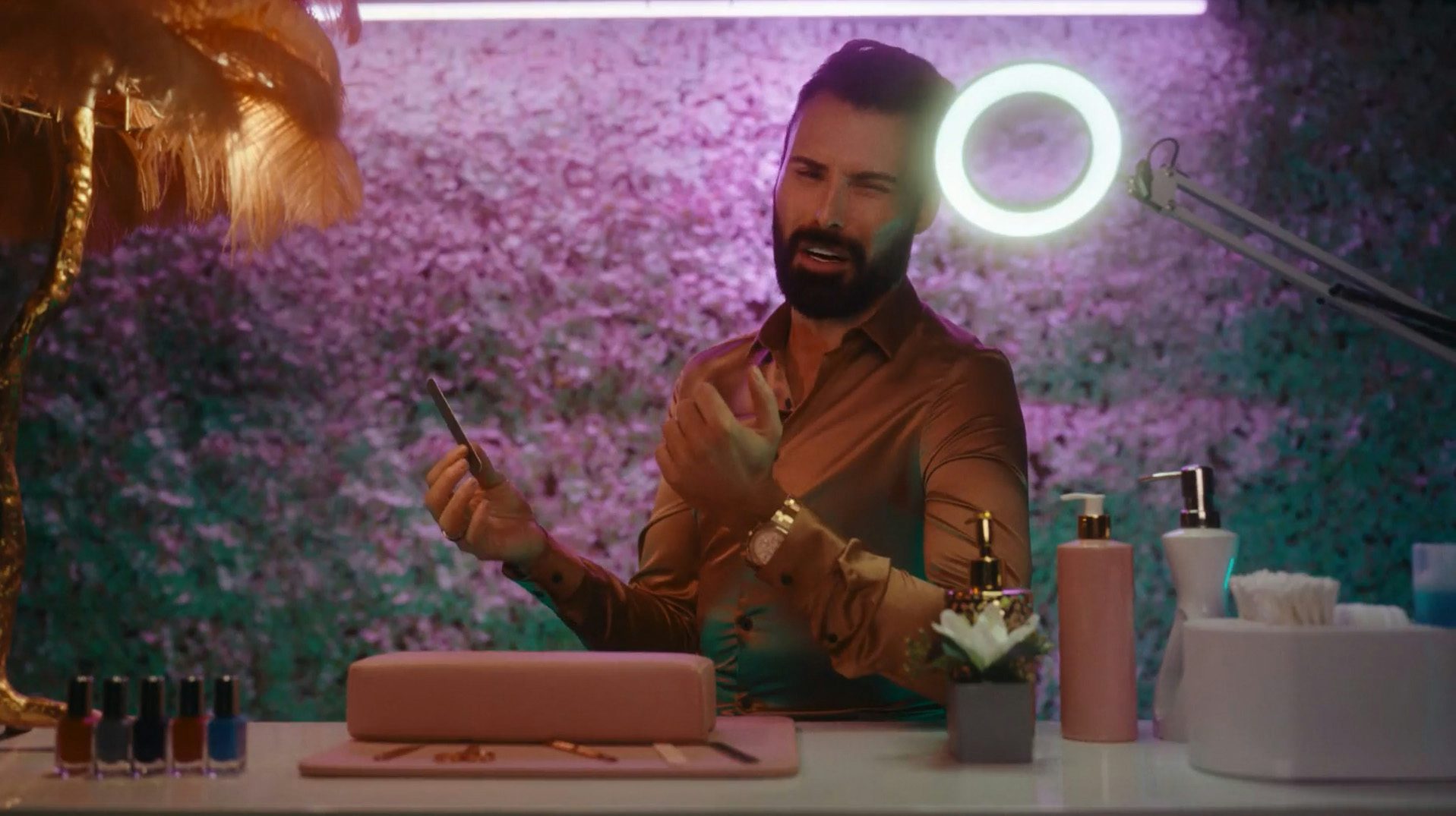 Still from the BBC Eurovision 2023 ad showing TV presenter Rylan holding a nail file while sat at a beauty station