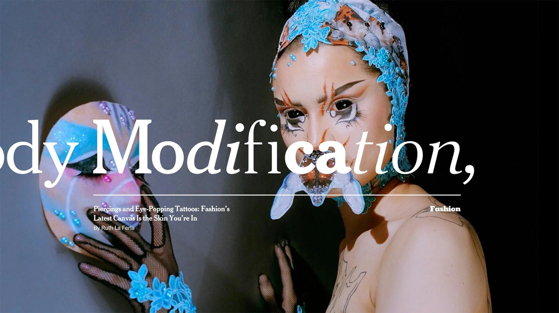 Still image from a New York Times brand campaign film showing an image of a pperson with ornate tattoos, decorated head cap, and fantastical facial accessories, holding an elaborate mask to the wall, with the words 'Modification' layered over the photo