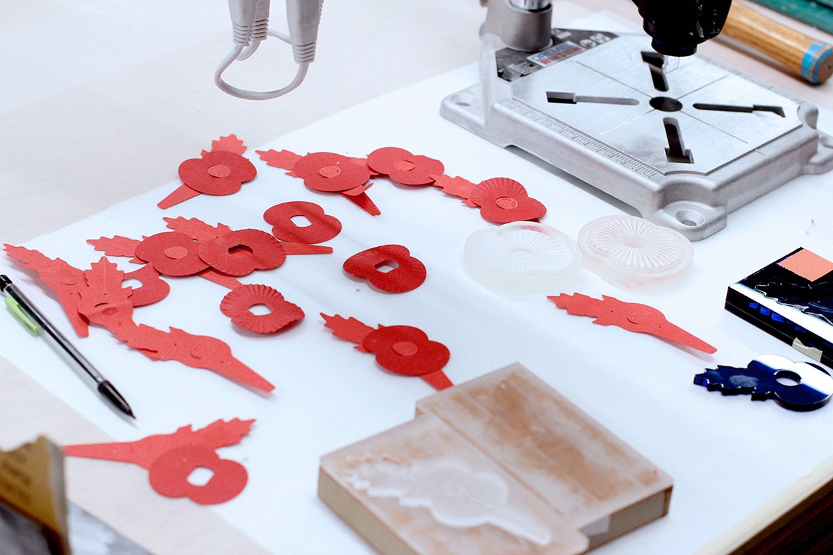 Image shows a tabletop covered in cut-out poppy shapes