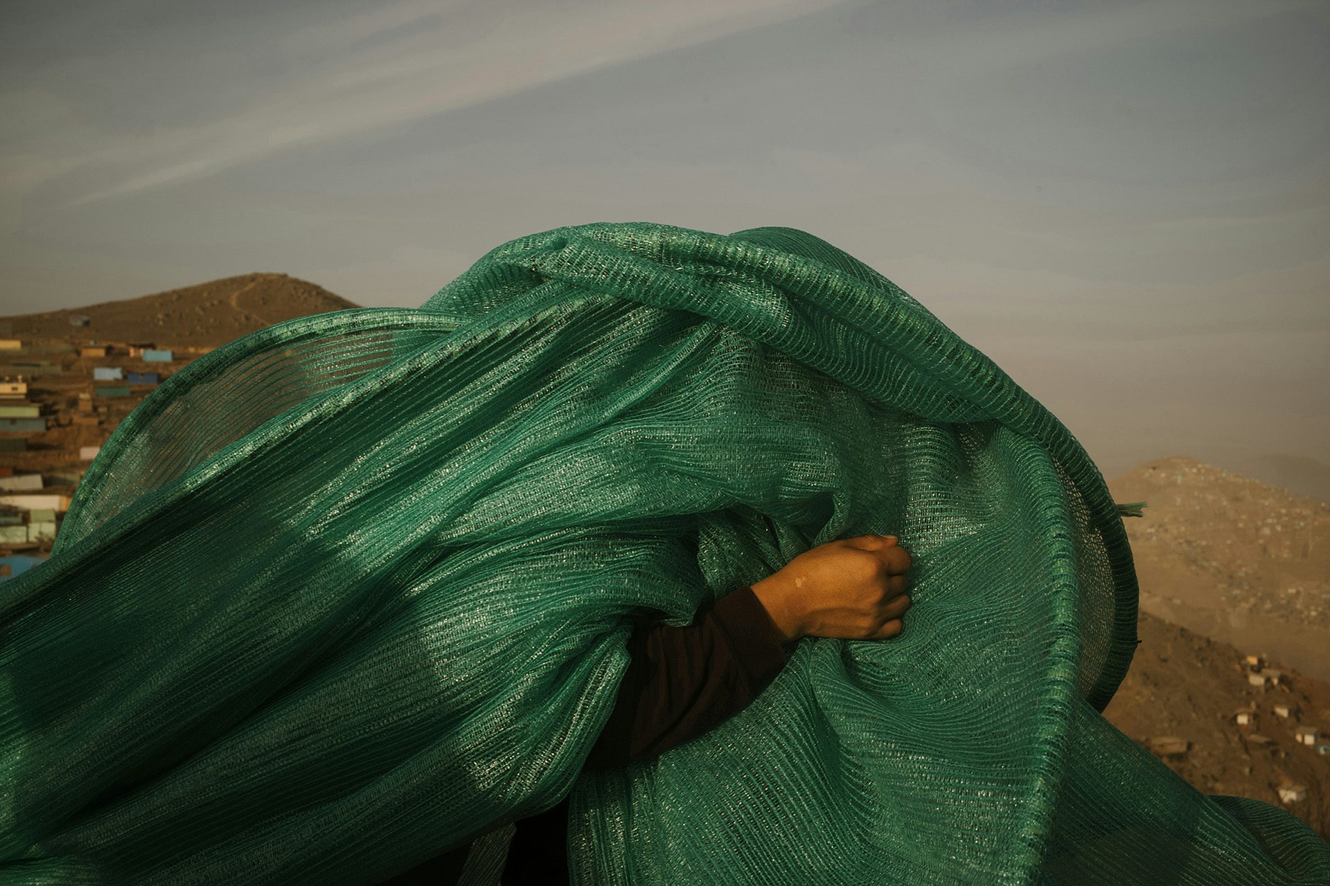 Photograph of a person carrying a green that's concealing their face, from the Sony World Photo Awards 2023