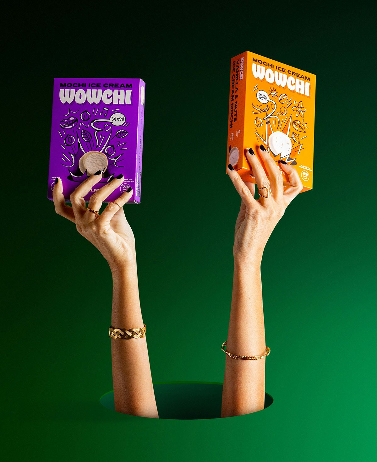 Image shows two hands protruding through a circular hole holding a purple and an orange box of Wowchi mochi in each hand, with line illustrations and mochi balls on the front