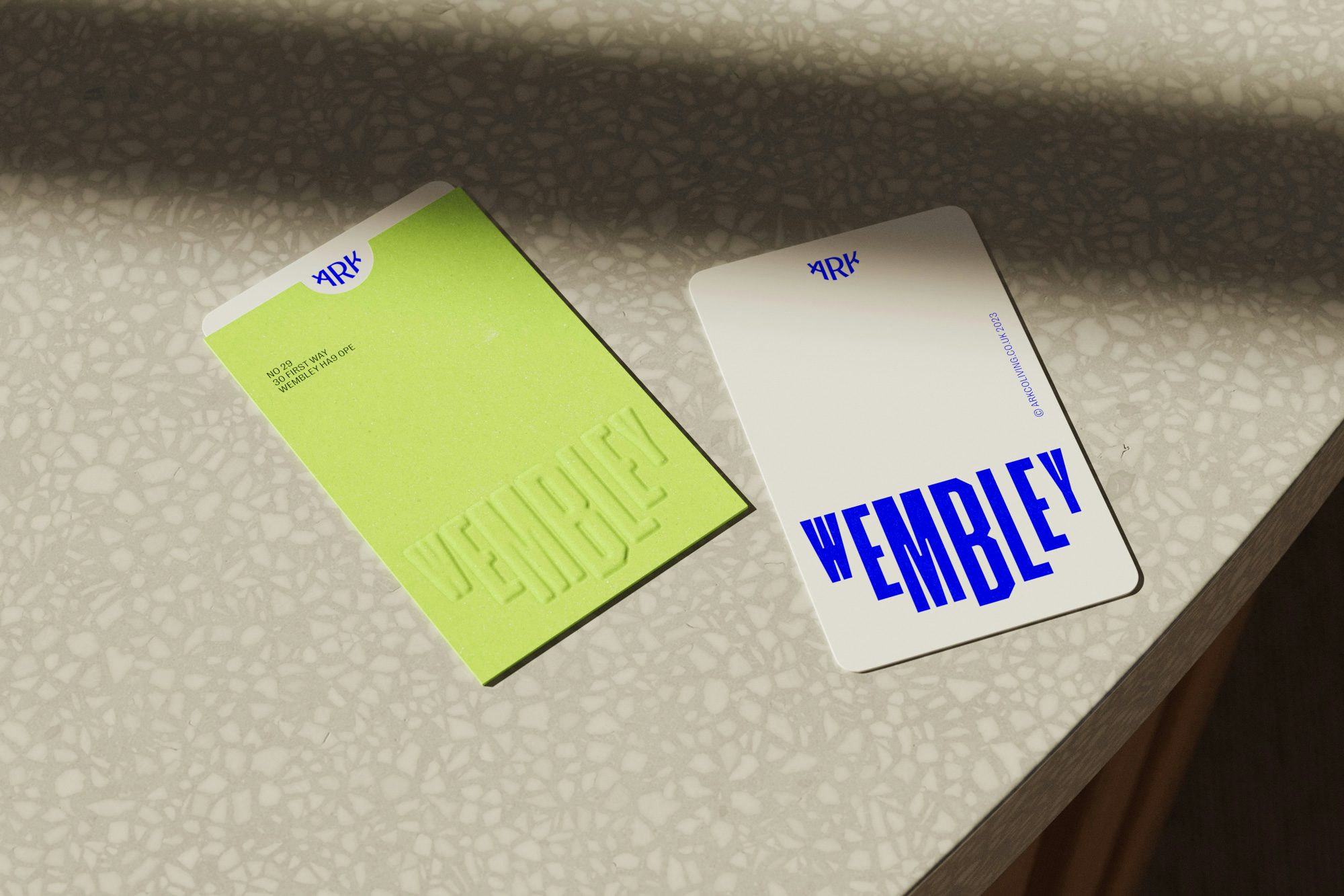 Image shows Ark branding on two pass cards, one lime green, one white with blue text, both featuring the word 'Wembley' arranged the shape of a smile