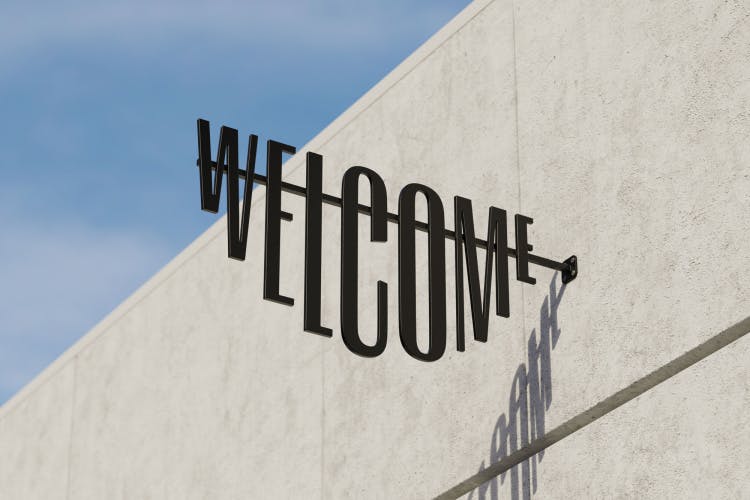 Image shows Ark branding on a black metal Welcome sign, whose letters are arranged in the shape of a smile