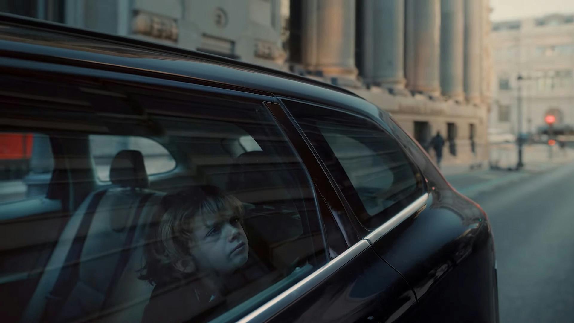 Image from Burger King campaign A Little More Confusing showing a child gazing out of the window of a black car driving through city streets. The image is taken from the outside