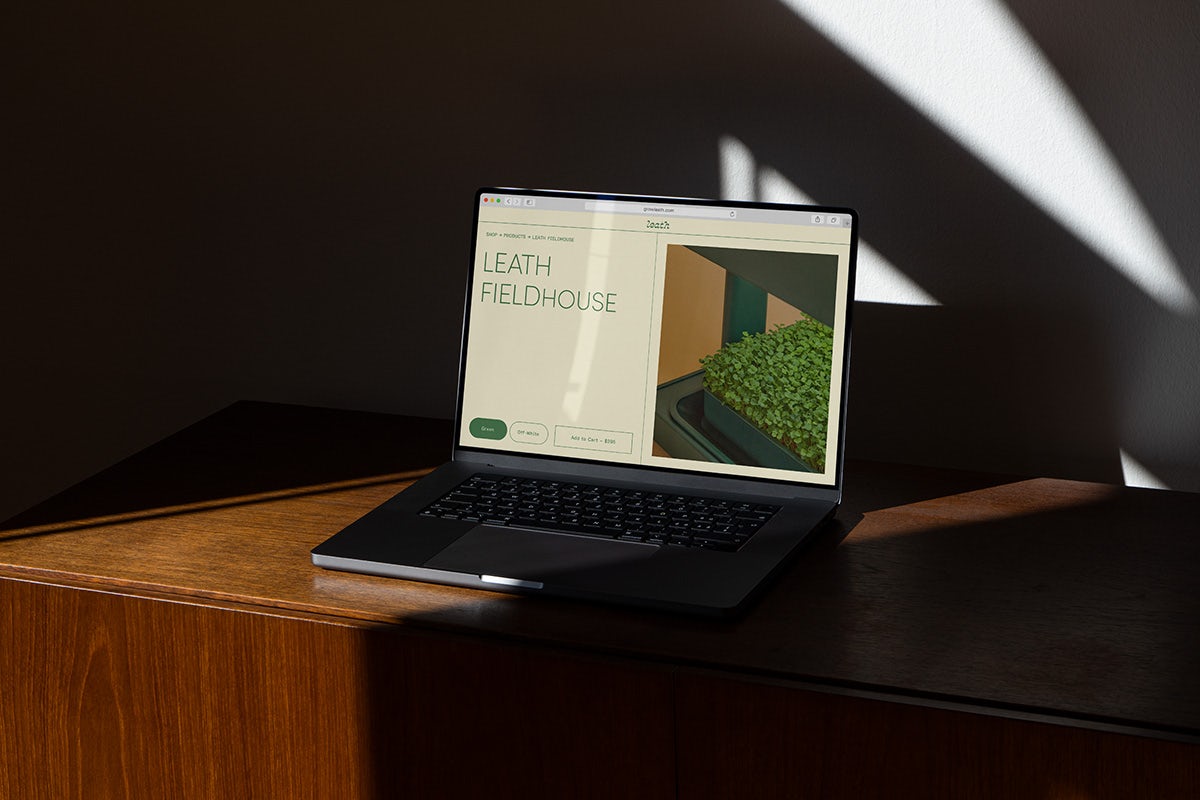 Image showing the branding for Leath, as seen on the brand website shown on a laptop resting on a dark wood table