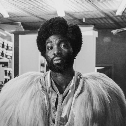 Black and white photograph by David Hurn showing Black Mirror star Paapa Essiedu in a light feather jacket and a skinny tie,