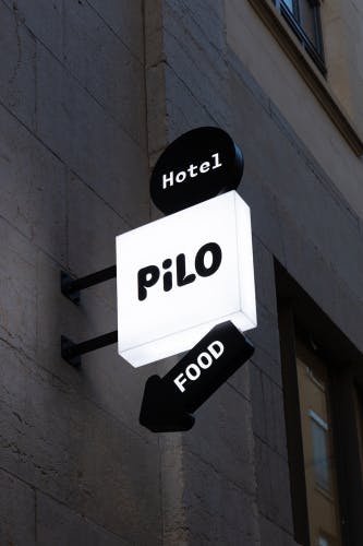 Photo of a Pilo hostel sign fixed to a wall, with additional signs that read hotel and food