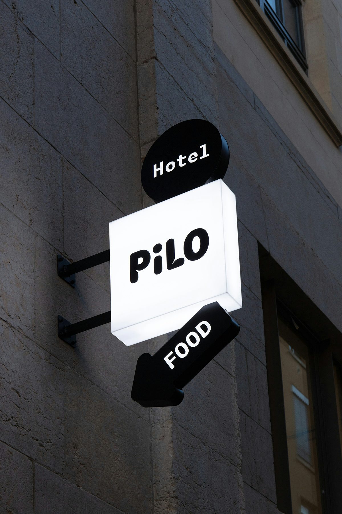 Photo of a Pilo hostel sign fixed to a wall, with additional signs that read hotel and food
