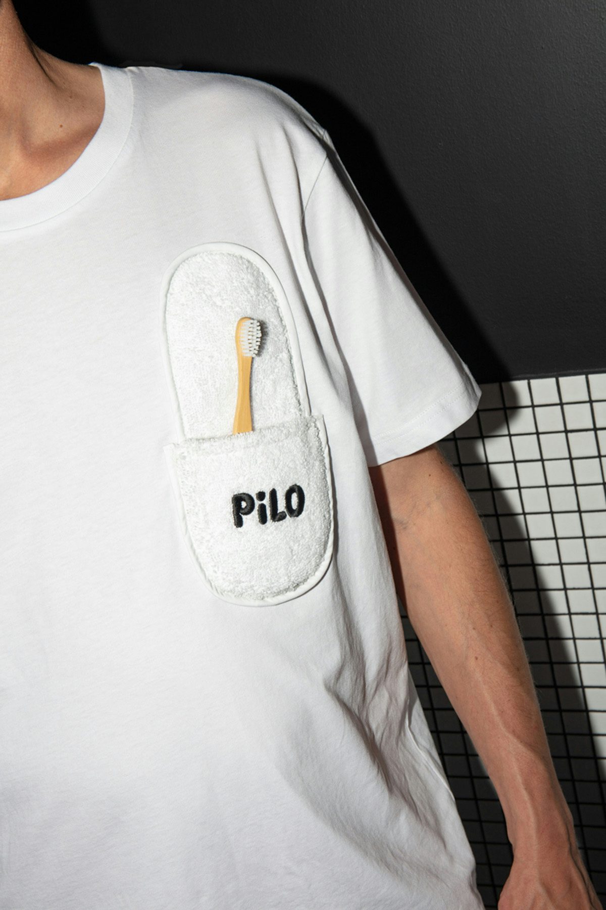 Photo showing Pilo's black bubbly font written on a slipper attached to a T-shirt in the place of a pocket