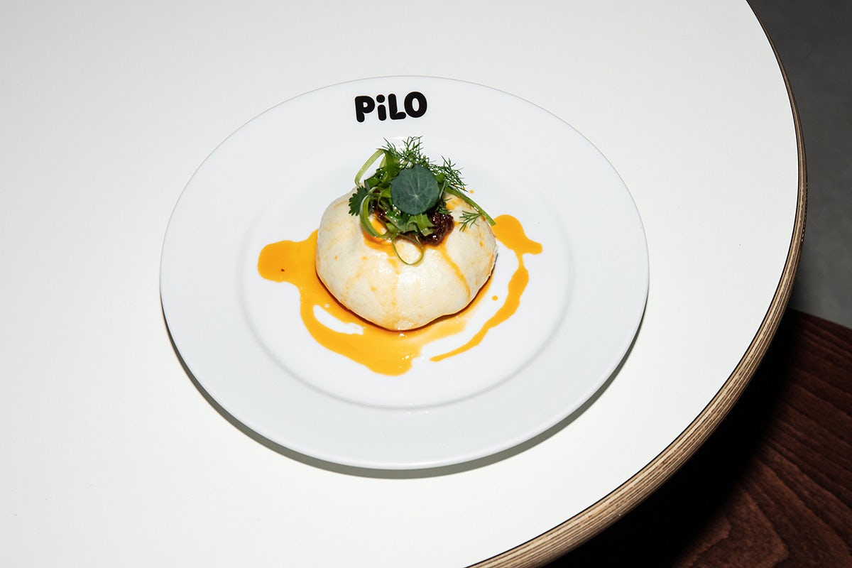 Photo of a white plate of food with the word Pilo written on the plate rim in black rounded font