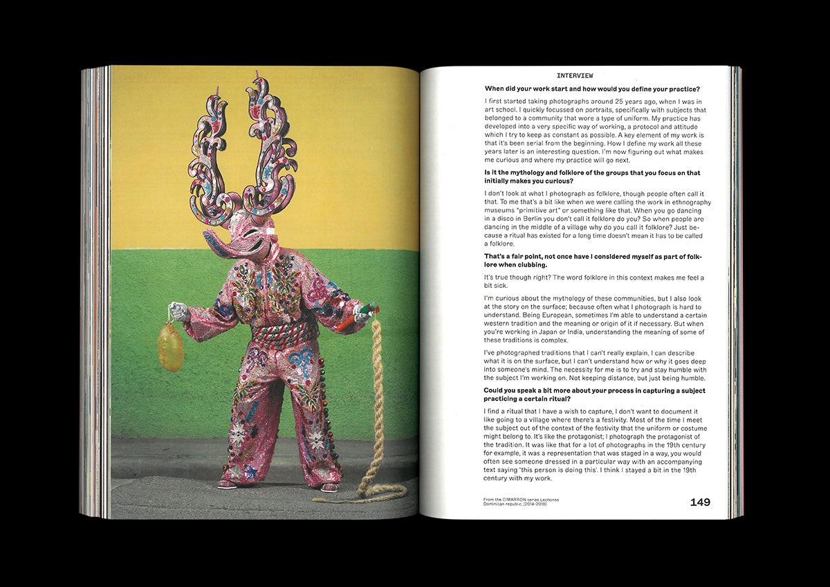Photo of a spread from ACV magazine showing a person wearing a pink ornate costume with headwear pointing up like ears, with text on the right hand page