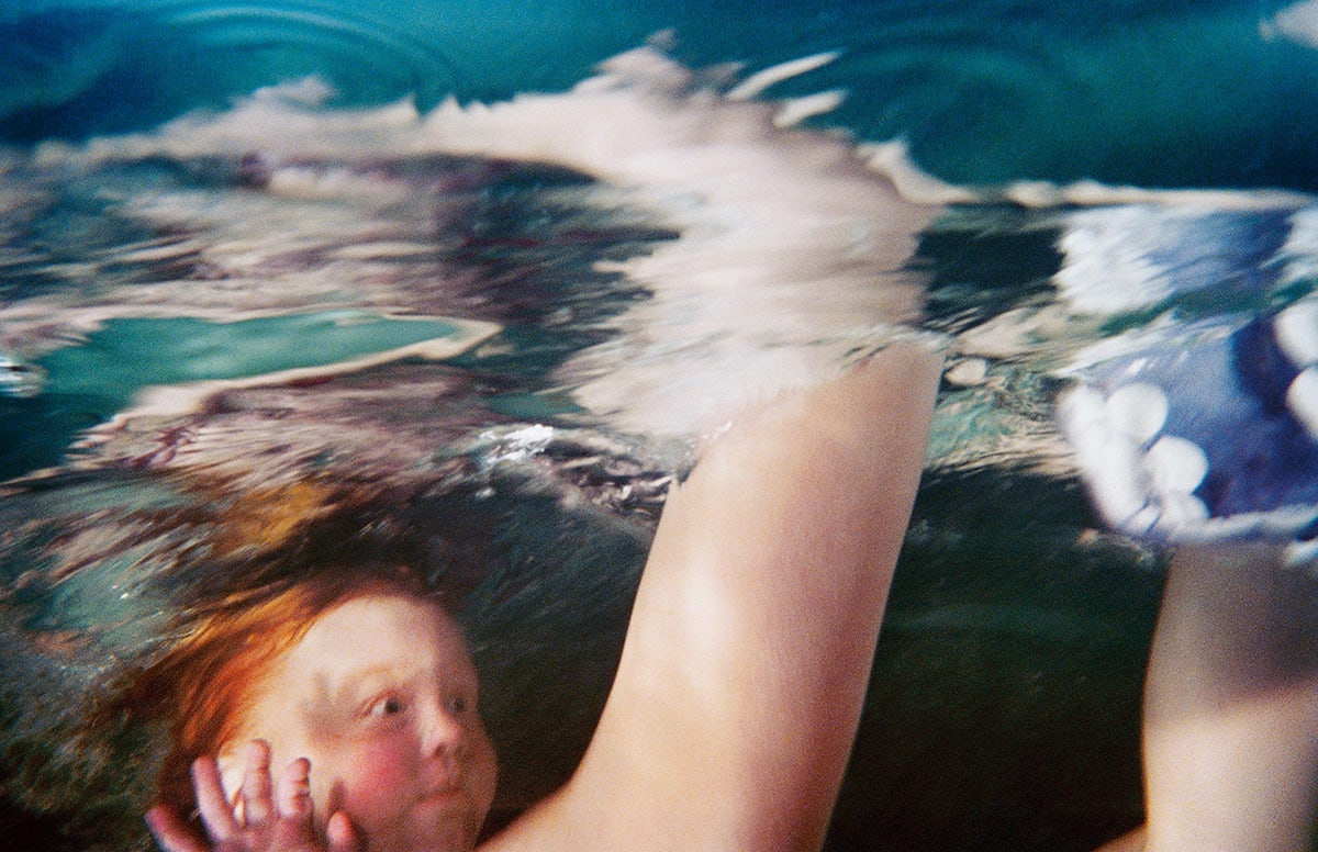 Photograph by Larry Sultan from his series Swimmers showing a young person with red hair underwater with their eyes wide open as though surprised