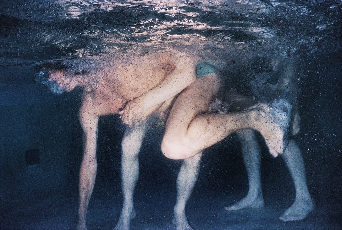 Photograph by Larry Sultan from his series Swimmers showing a person floating in a swimming pool touching the bottom of the pool with one arm