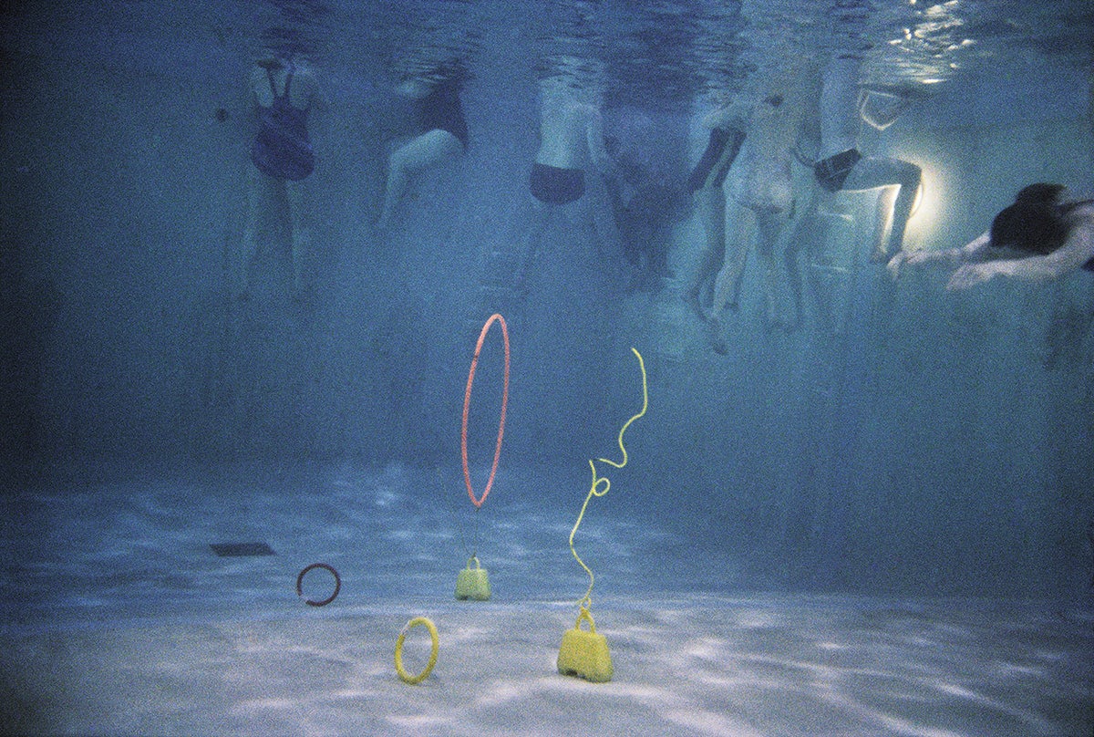 Photograph by Larry Sultan from his series Swimmers showing people's bodies in a swimming pool with pool hoops and equipment at the bottom of the pool