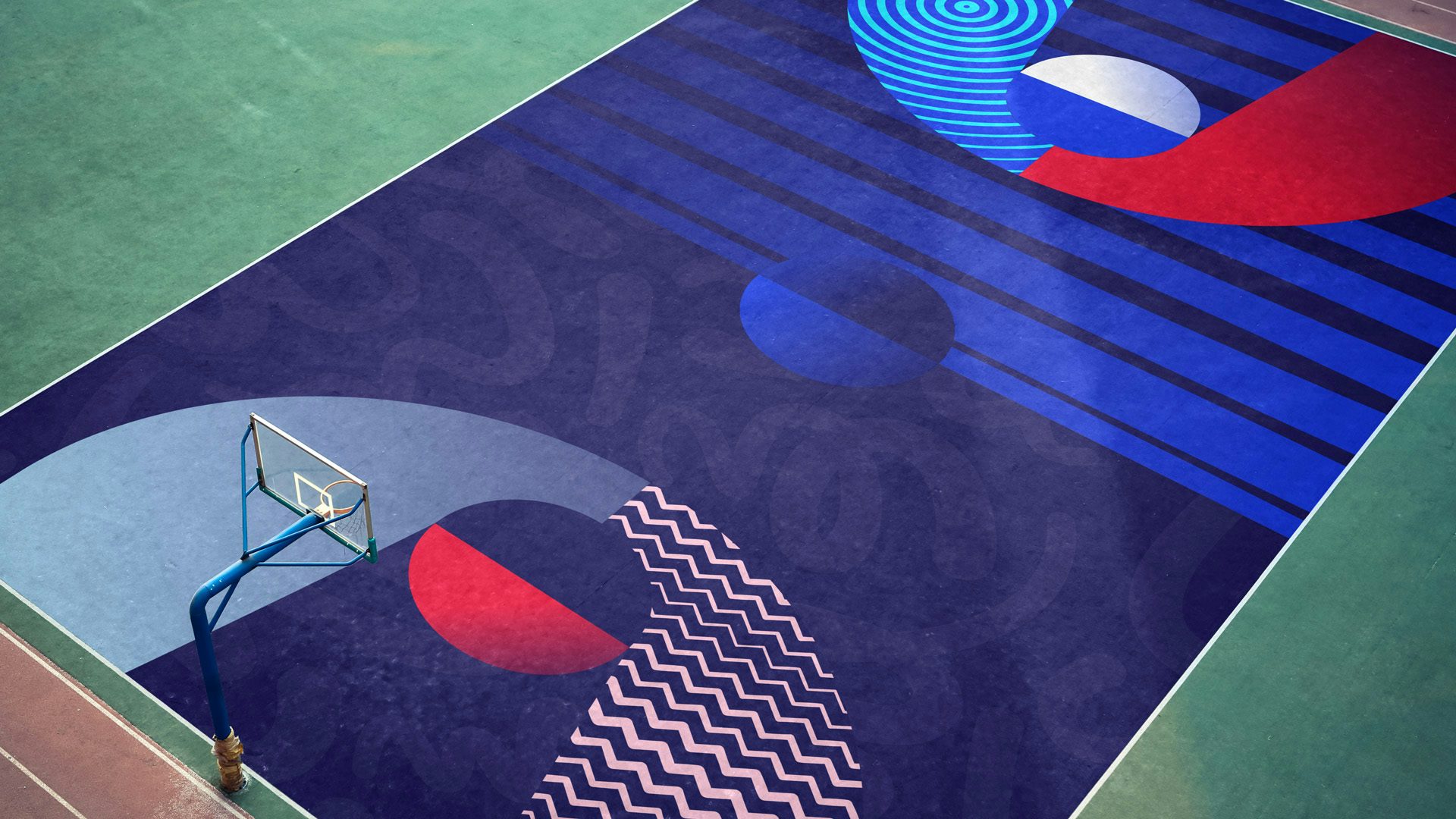 Aerial photo of a basketball court decorated in the style of the Team GB rebrand, with blue, red, white, and pink graphic patterns